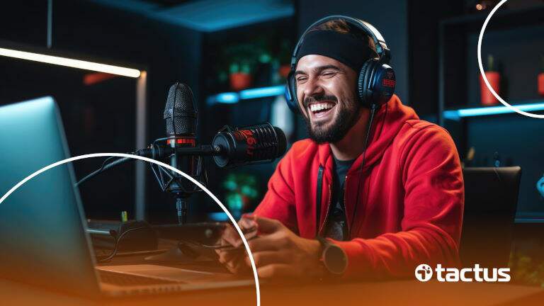 Imagem mostra jovem rapaz sorrindo com controle de videogame na mão e aparatos de podcast, simulando a importância de ter uma Contabilidade para Streamer