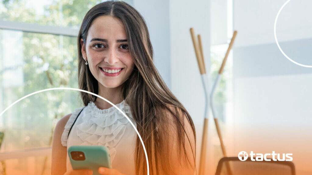 Imagem mostra jovem empresária sorrindo para a câmera com celular na mão, simbolizando como abrir cnpj para social media