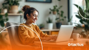 Imagem mostra jovem mulher sorridente com notebook no colo para ilustrar como sacar dinheiro na Kiwify