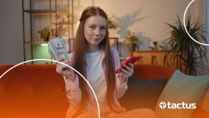 Imagem mostra menina com celular e dólares na mão, sorrindo, para simular como ganhar dinheiro no TikTok