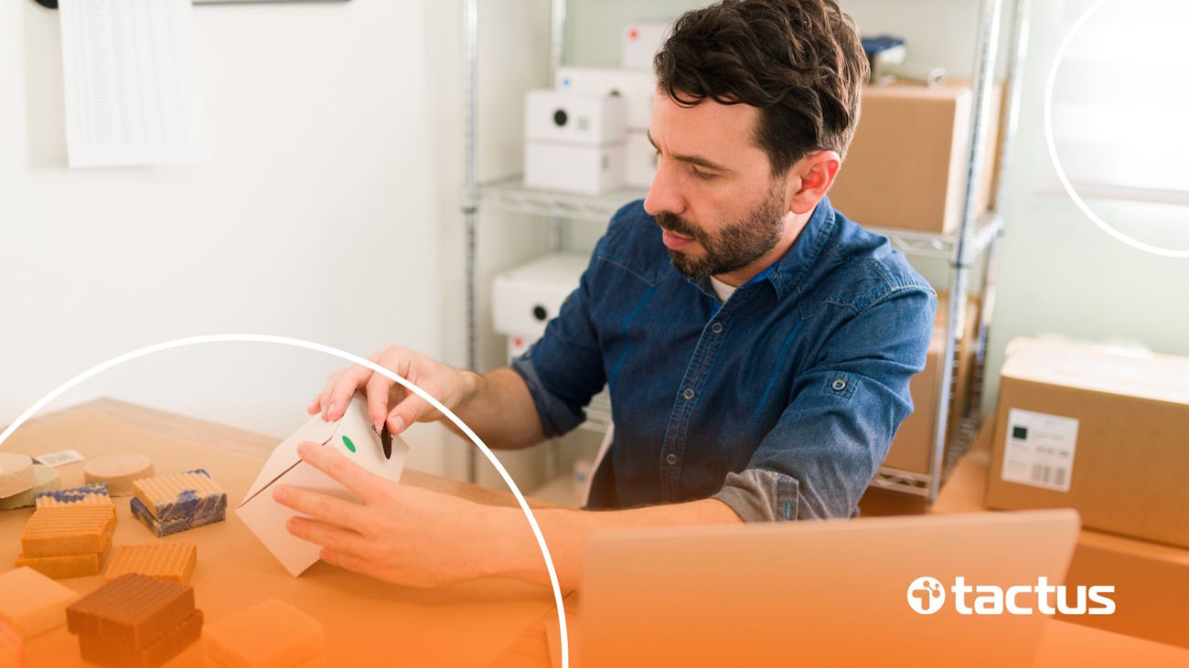 Imagem mostra pequeno empresário embalando compras na mesa da sua casa cercado por caixas, para ilustrar que MEI pode vender no Mercado Livre