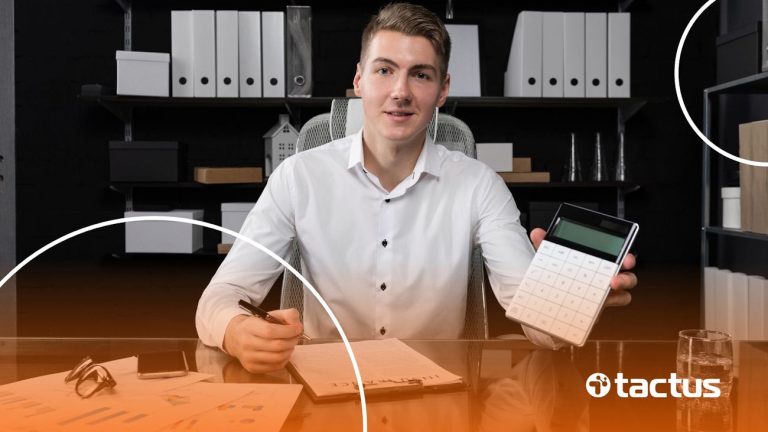 Imagem mostra jovem de negócios em sua mesa com calculadora na mão olhando para a câmera, para simular o que muda com a reforma tributária para representantes comerciais
