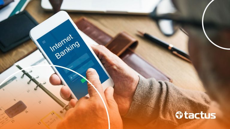 Imagem mostra empresário mexendo no celular com a tela escrita "Internet Banking", para ilustrar a forma correta de transferir dinheiro da empresa para conta pessoal