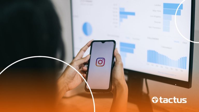 Imagem mostra mãos de jovem mexendo no Instagram, com tela à frente de computador repleta de gráficos, para simbolizar como monetizar o Instagram