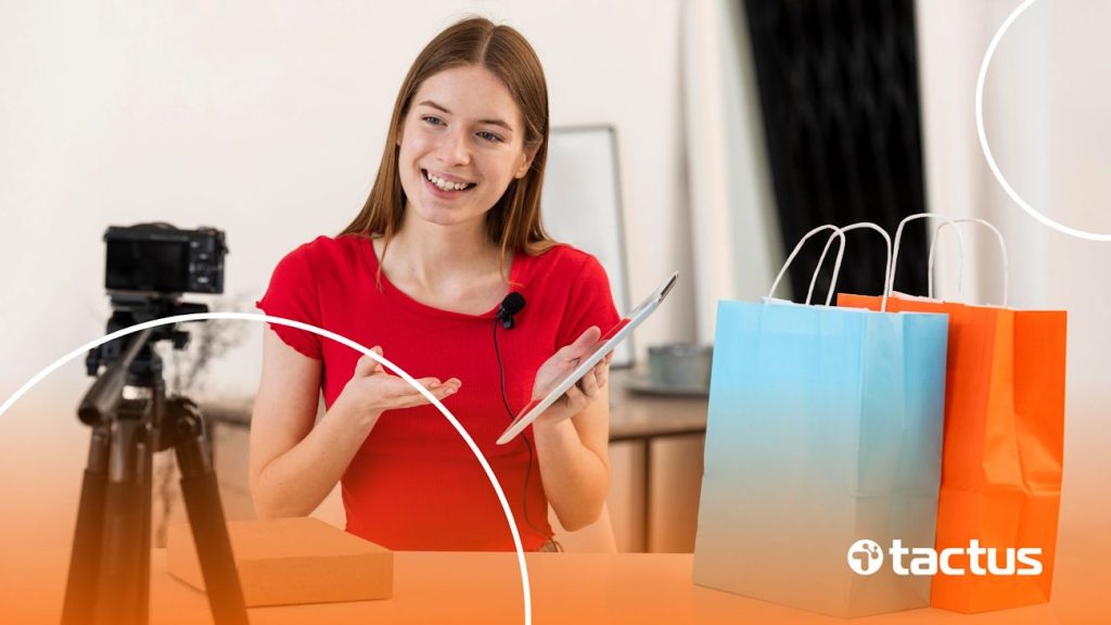 Jovem sorrindo para a câmera com sacolas à sua frente, para simbolizar como funciona o youtube shopping