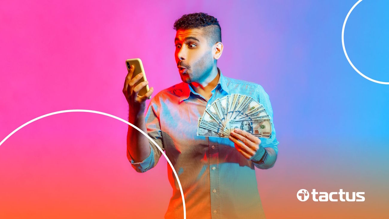 Homem com celular e dólares na mão para ilustrar se quem paga mais é TikTok ou Kwai