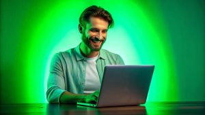 Homem sorrindo olhando para o computador com fundo verde atrás, cor da Kiwify, para simular como vender na Kiwify
