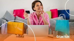 Mulher sorrindo em meio a sacolas e em frente notebook com rosto pensativo, como se perguntasse se precisa de CNPJ para vender na Shopee