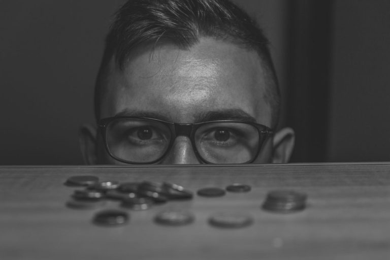 Pessoa com metade da cara amostra e com moedas à sua frente, para simbolizar a distribuição de lucros disfarçada