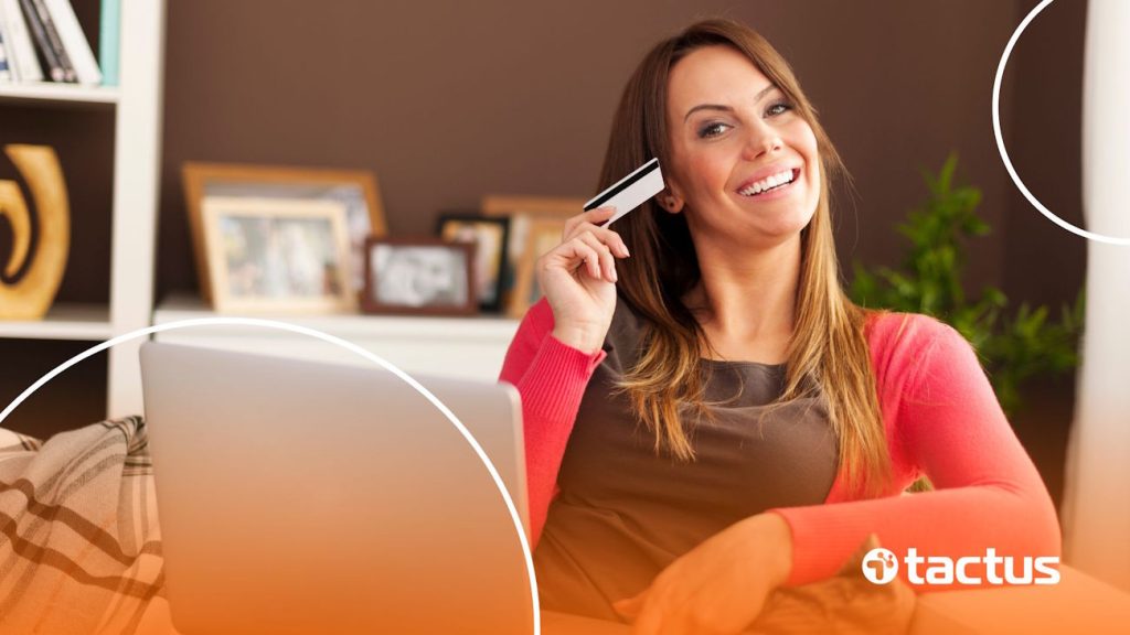 Imagem mostra mulher sorrindo com cartão de crédito na mão, para simbolizar os nichos que vendem o ano todo