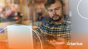 Homem jovem mexendo no celular escondido pelo notebook, para ilustrar como vender como afiliado sem aparecer